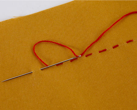 A single line of running stitches in red thread on yellow fabric